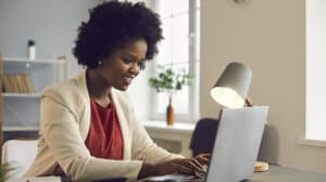 Young afro american businesswoman working on laptop with electronic documents.