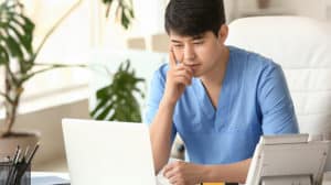 Male medical assistant working on laptop in clinic