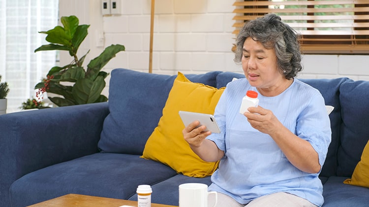 Senior asian woman holding bottle of pill make video conference
